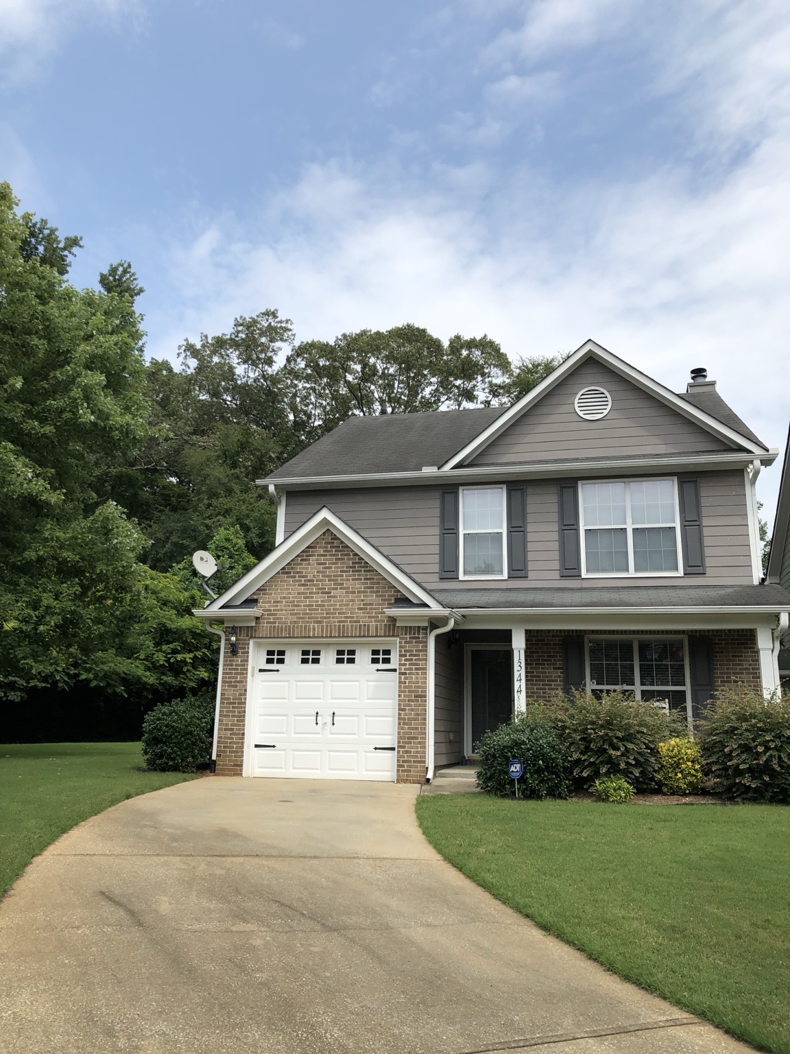 A gray home with a white garage and green lawn